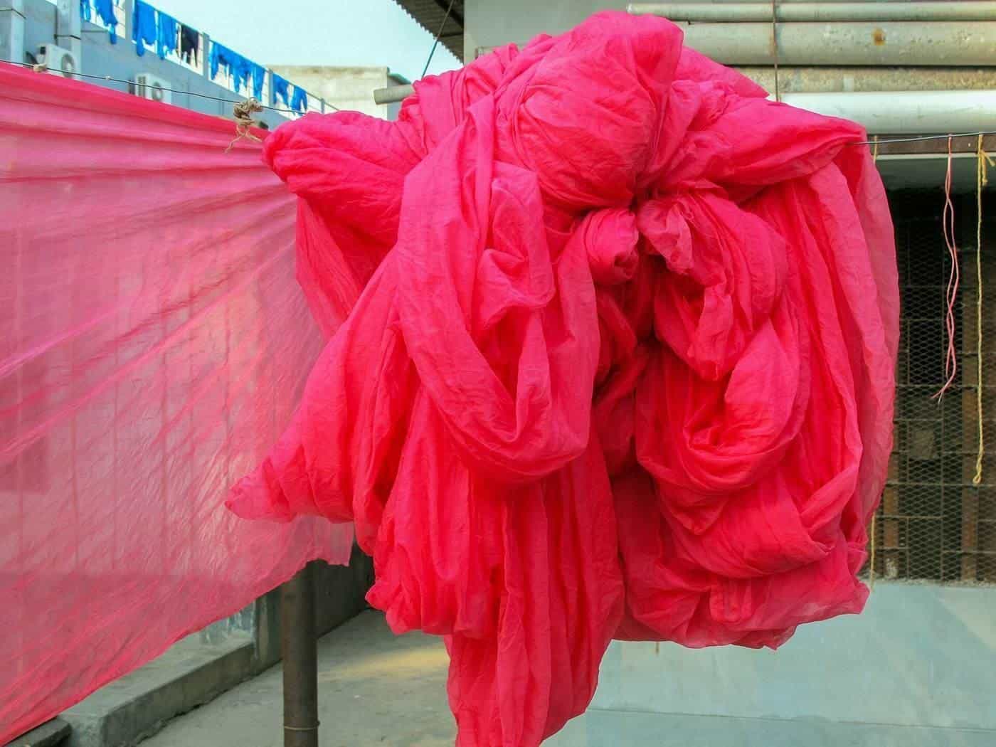 Bright pink silk fabric hanging up to dry