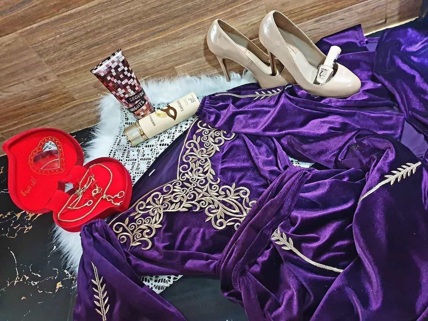 A purple embroidered caftan laid out with shoes and accessories